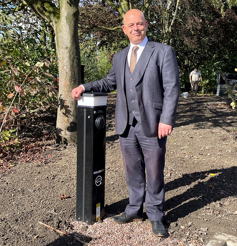 Councillor Greg Brackenridge next to one of the electric vehicle charging point for the apartments